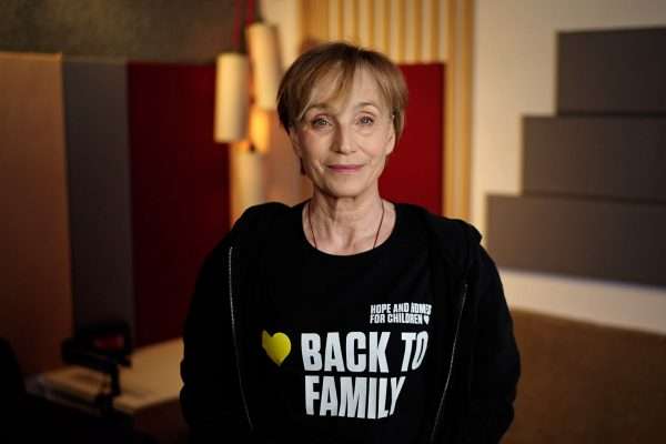 Actor Kristin Scott Thomas wearing a black t-shirt with the caption 'Back to Family'