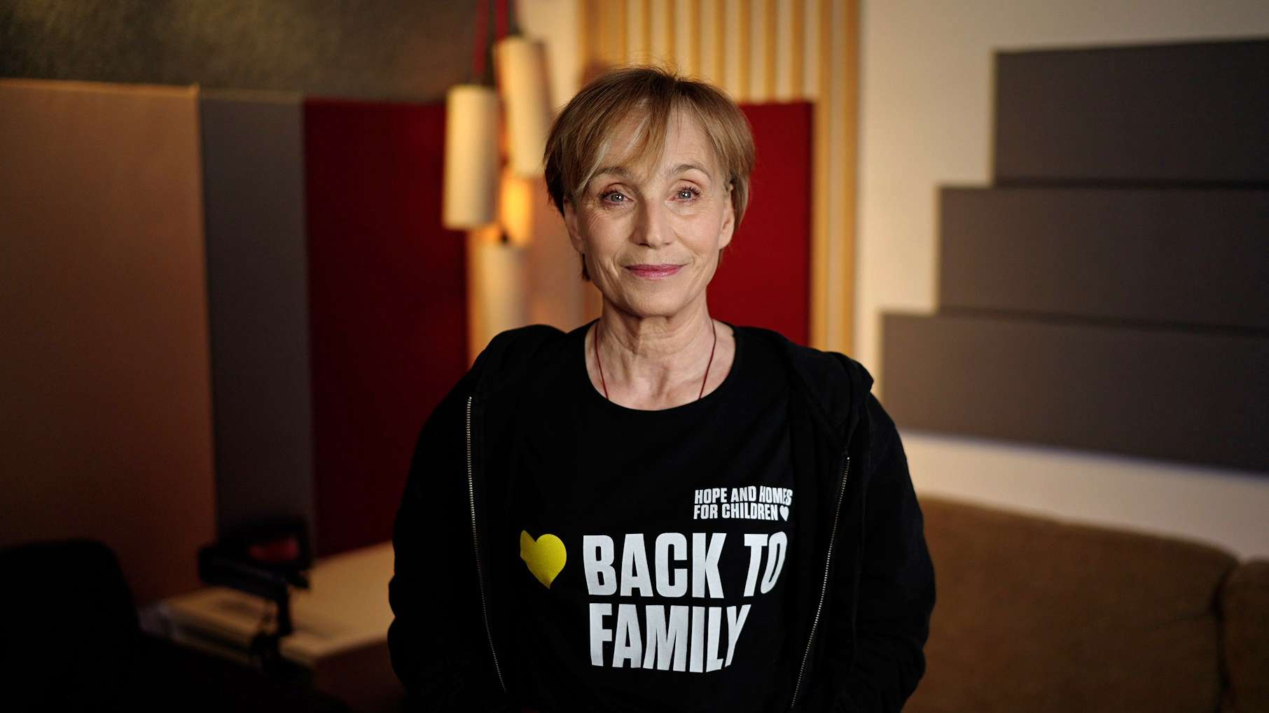 Actor Kristin Scott Thomas wearing a black t-shirt with the caption 'Back to Family'